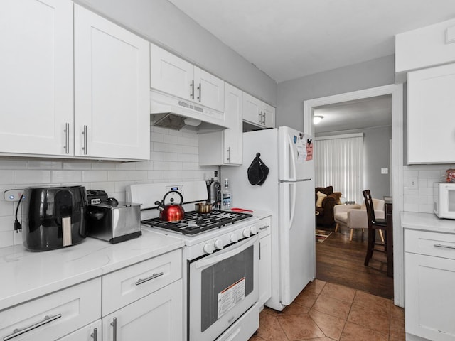 kitchen featuring tasteful backsplash, white appliances, white cabinetry, light tile patterned flooring, and under cabinet range hood