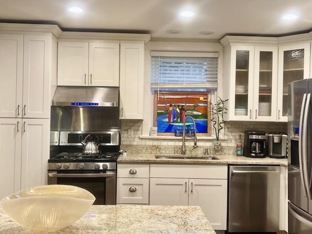 kitchen with a sink, stainless steel appliances, white cabinetry, and under cabinet range hood