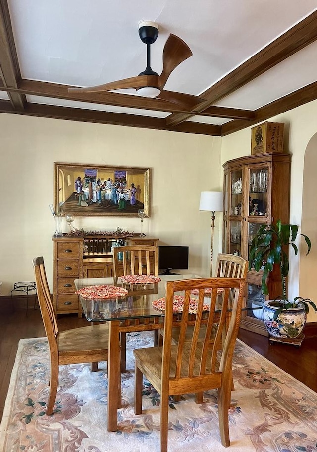 dining room featuring wood finished floors, beam ceiling, ceiling fan, arched walkways, and coffered ceiling