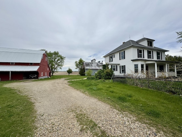 view of side of property with a barn, an outdoor structure, dirt driveway, and fence