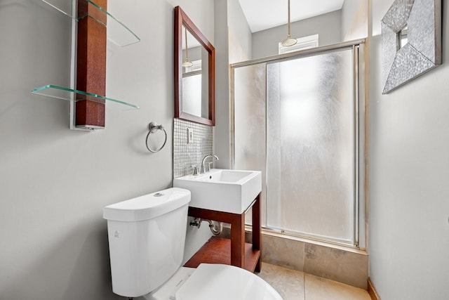 bathroom with a sink, toilet, and a shower stall