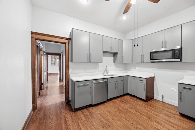 kitchen featuring a sink, gray cabinets, wood finished floors, and stainless steel appliances
