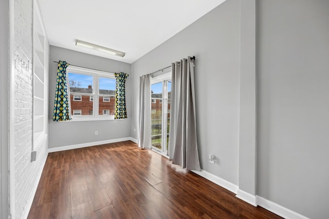 empty room featuring baseboards and dark wood-style floors