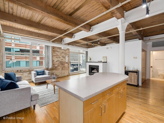 kitchen with light wood-type flooring, brick wall, open floor plan, a kitchen island, and wooden ceiling