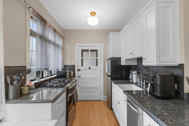 kitchen with appliances with stainless steel finishes, a sink, white cabinetry, and a wealth of natural light