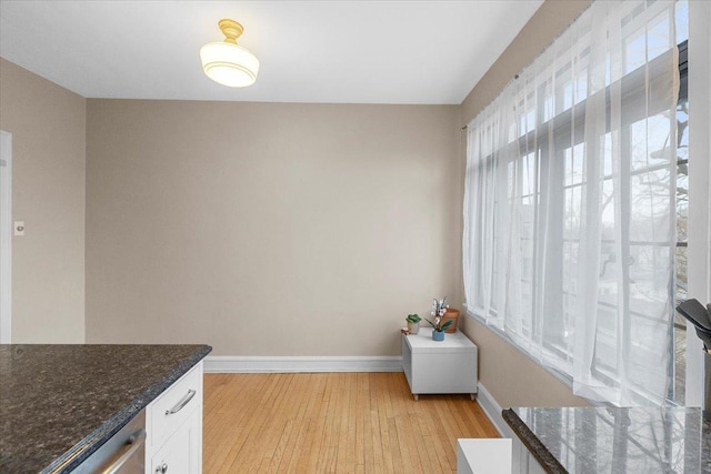 unfurnished dining area featuring light wood-style floors and baseboards