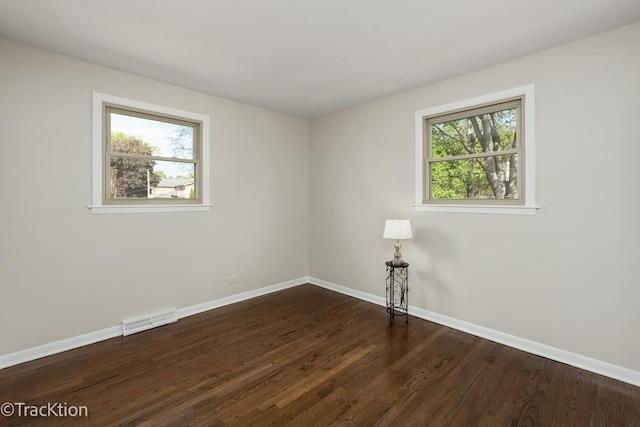 empty room with baseboards and dark wood-type flooring