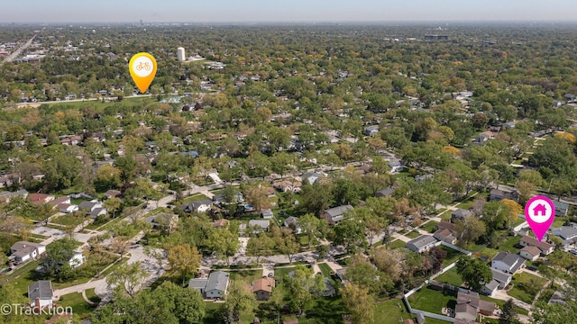 aerial view of property and surrounding area featuring a forest and nearby suburban area