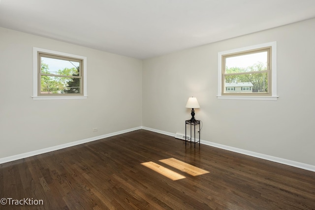 unfurnished room with plenty of natural light, baseboards, and dark wood finished floors