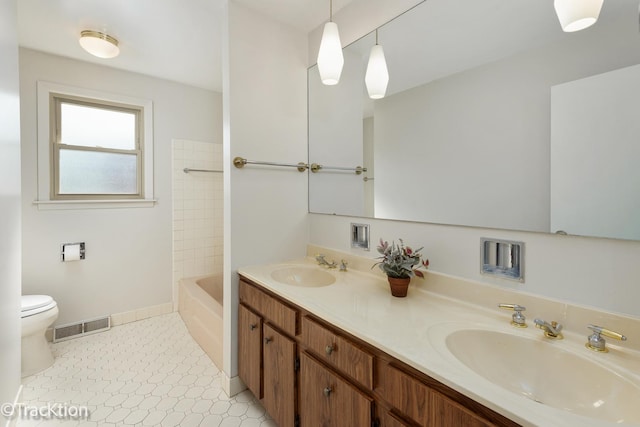 full bath with toilet, double vanity, and baseboards