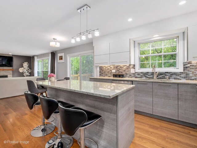 14 Wildflower Way, Streamwood, IL 60107 - kitchen with a sink, a kitchen breakfast bar, decorative backsplash, modern cabinets, and decorative light fixtures