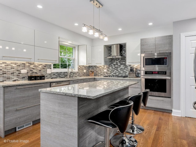 14 Wildflower Way, Streamwood, IL 60107 - kitchen featuring stainless steel appliances, modern cabinets, wall chimney exhaust hood, a breakfast bar, and a center island