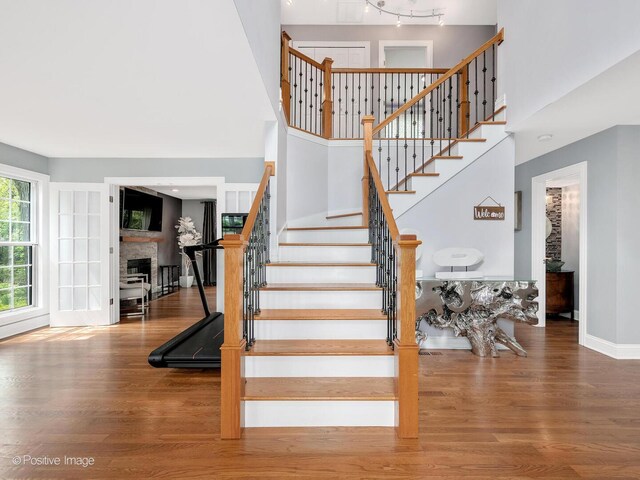14 Wildflower Way, Streamwood, IL 60107 - staircase with a towering ceiling, wood finished floors, a fireplace, and baseboards