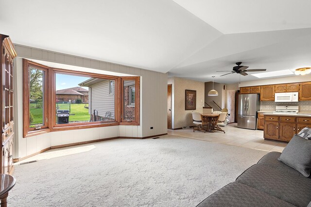 living room with visible vents, ceiling fan, lofted ceiling, and light carpet