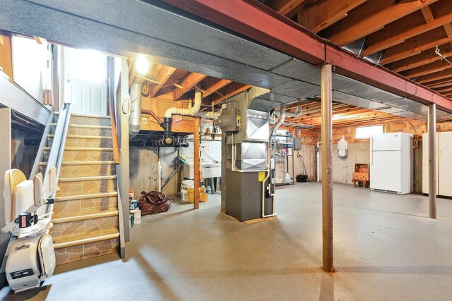 basement with stairway, heating unit, and freestanding refrigerator