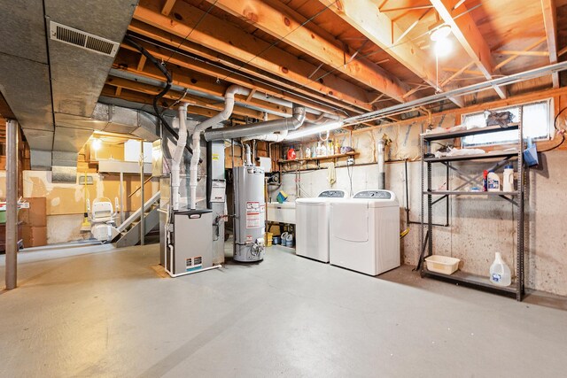 unfinished below grade area featuring visible vents, heating unit, washer and clothes dryer, and water heater