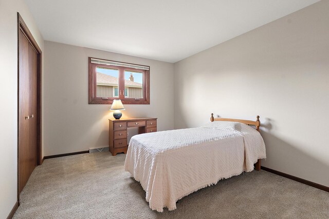bedroom with baseboards, light carpet, a closet, and visible vents
