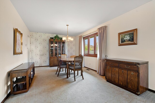 dining space featuring light colored carpet, baseboards, a notable chandelier, and visible vents