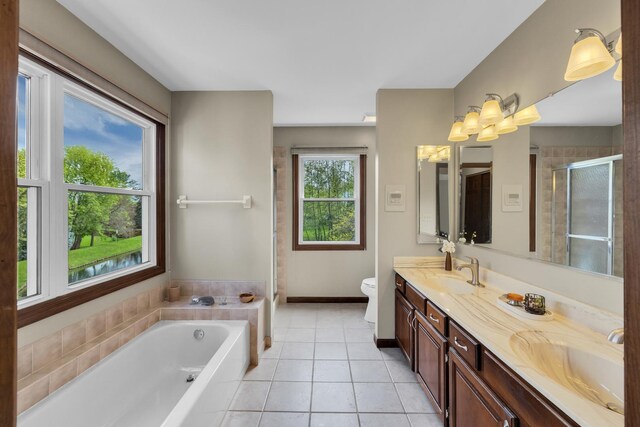 bathroom with tile patterned floors, a bath, double vanity, toilet, and a stall shower