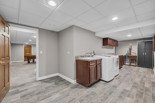 laundry area with light wood finished floors, baseboards, washer / clothes dryer, a sink, and recessed lighting