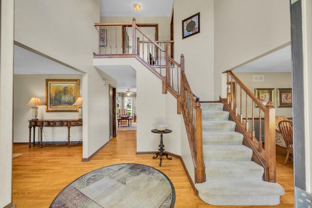 stairway with wood finished floors, a high ceiling, and baseboards