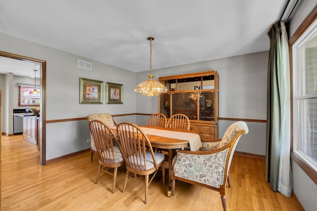 dining space featuring light wood-style flooring, a chandelier, and baseboards