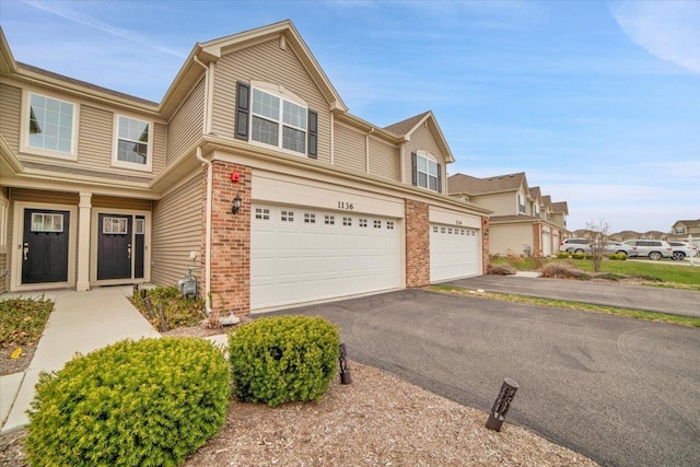 view of property featuring a garage, aphalt driveway, and brick siding