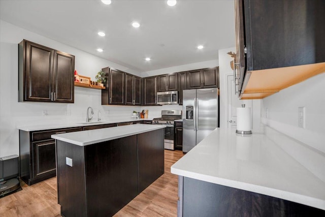 kitchen featuring a sink, light countertops, appliances with stainless steel finishes, dark brown cabinets, and light wood-style flooring
