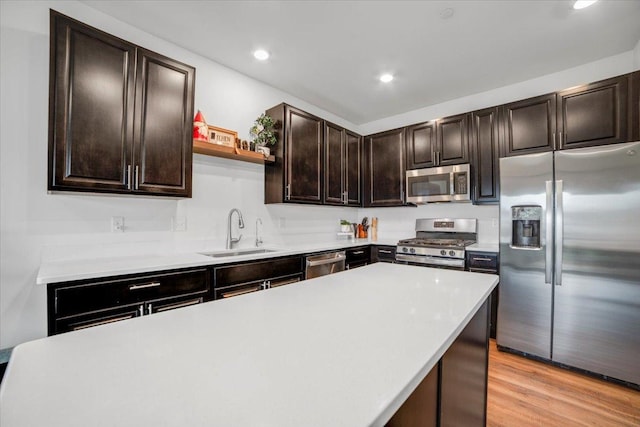 kitchen with light countertops, dark brown cabinets, light wood-style floors, stainless steel appliances, and a sink