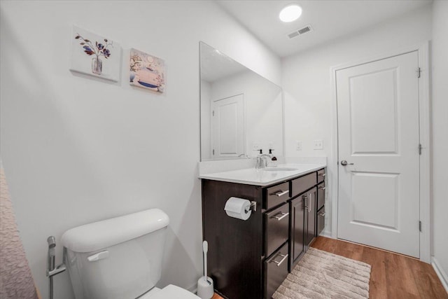 bathroom featuring vanity, visible vents, toilet, and wood finished floors