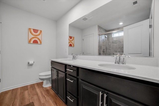 full bathroom featuring a sink, toilet, a stall shower, and wood finished floors
