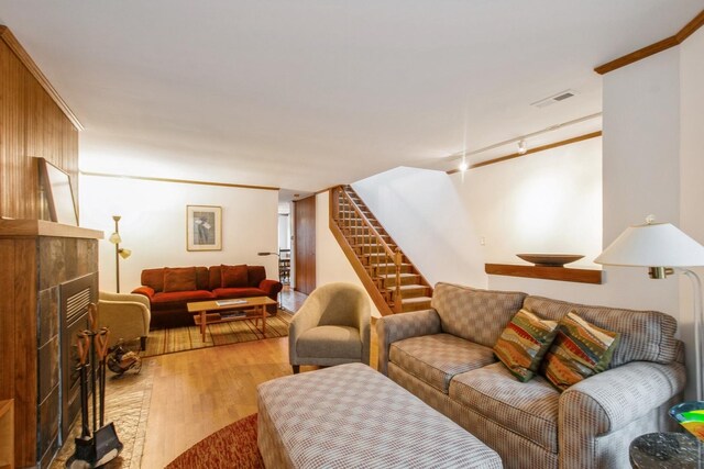 801 S Plymouth Ct Unit P, Chicago, IL 60605 - living room featuring visible vents, a tiled fireplace, crown molding, stairway, and wood finished floors