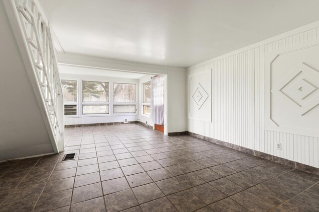 spare room with a decorative wall and visible vents