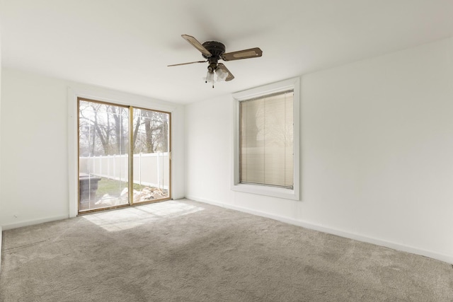 carpeted spare room with baseboards and a ceiling fan