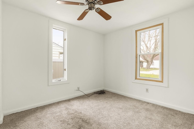 carpeted spare room featuring baseboards and a ceiling fan