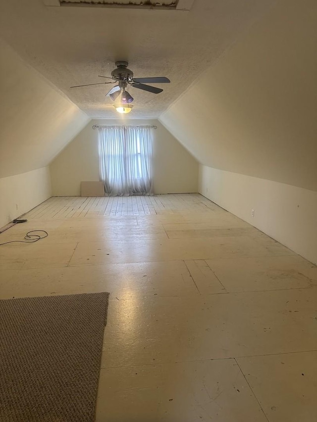 bonus room featuring a textured ceiling, a ceiling fan, and lofted ceiling
