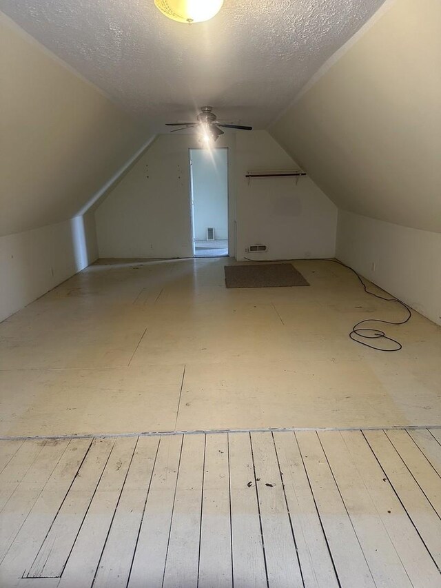 bonus room featuring a textured ceiling, hardwood / wood-style floors, a ceiling fan, and lofted ceiling
