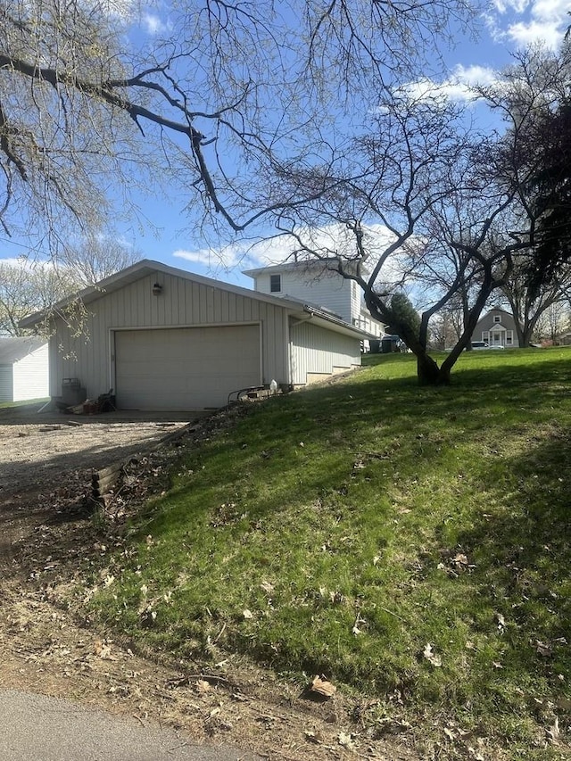 view of side of home with a yard, driveway, and an outbuilding