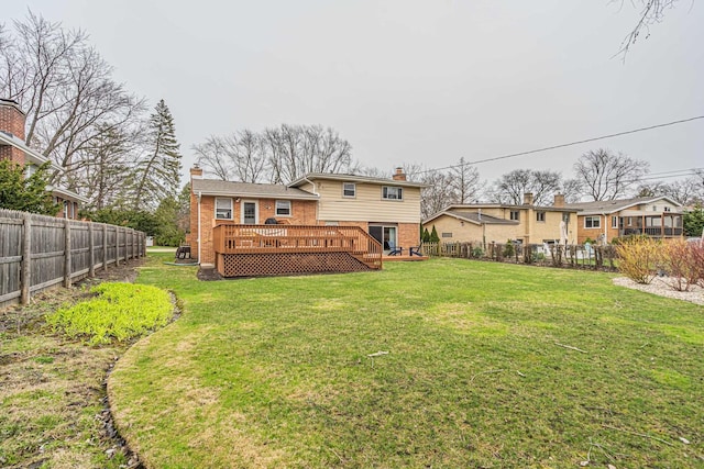 back of house featuring a chimney, a lawn, a deck, fence private yard, and brick siding