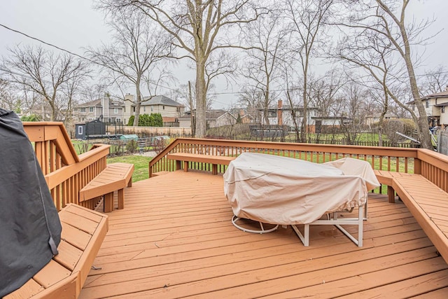 wooden deck with a residential view, a trampoline, a fenced backyard, and outdoor dining space