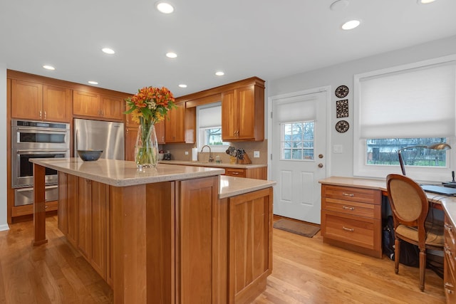 kitchen featuring appliances with stainless steel finishes, a sink, a warming drawer, and light wood-style floors