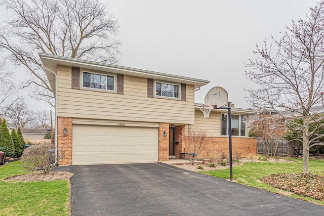 tri-level home with fence, an attached garage, aphalt driveway, brick siding, and a front yard