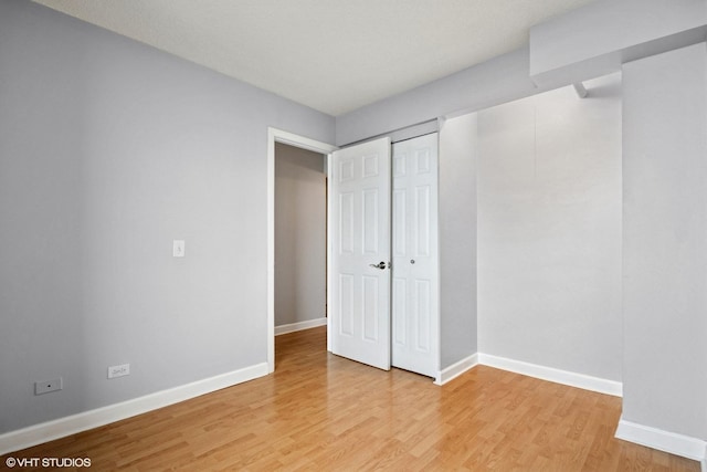 unfurnished bedroom with a closet, light wood-style flooring, and baseboards