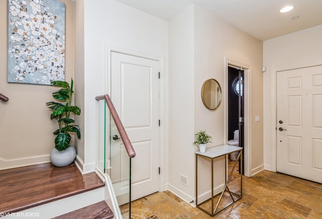 foyer featuring stone finish flooring, baseboards, and recessed lighting