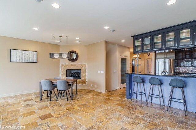 kitchen with stone tile flooring, a breakfast bar, freestanding refrigerator, and recessed lighting