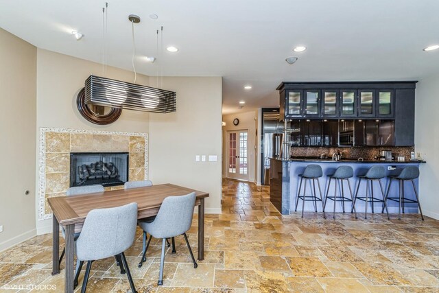 dining area featuring stone tile floors, baseboards, a fireplace, and recessed lighting