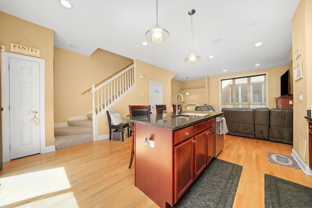 kitchen featuring a sink, dishwasher, light wood-style flooring, open floor plan, and reddish brown cabinets
