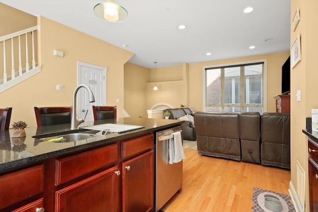 kitchen featuring reddish brown cabinets, stainless steel dishwasher, a sink, light wood finished floors, and open floor plan