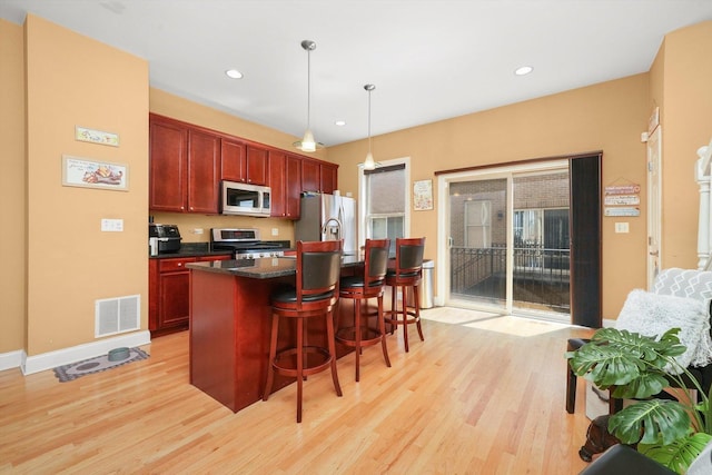 kitchen featuring dark countertops, appliances with stainless steel finishes, visible vents, and light wood-style floors