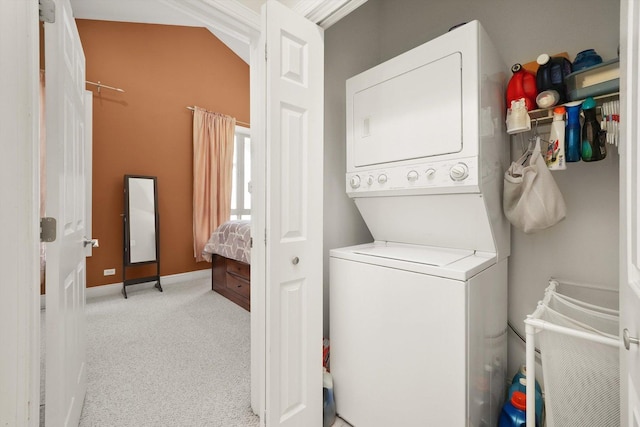 clothes washing area with baseboards, light carpet, stacked washer / drying machine, and laundry area